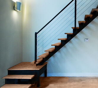 The upper units feature a striking staircase consisting of solid wood treads cantilevered from a central steel support. The modern aesthetic is completed with steel cable railings. Modern stair