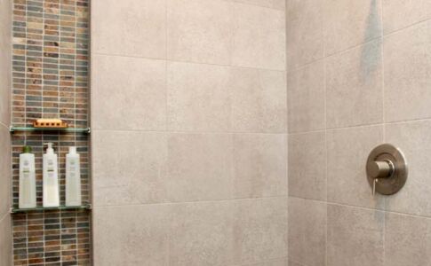 Custom tilework accentuates a shower niche and echoes slate ledger used elsewhere on the interior and exterior of the home. Photo of custom tiled shower