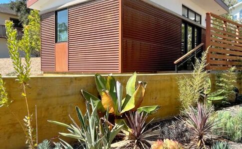 The exterior of this studio ADU features low-maintenance, fire-resistive materials and drought-tolerant landscaping. The corrugated steel siding will rust until all surfaces are fully oxidized, then it will rust no further. Photo of an Accessory Dwelling Unit (ADU)