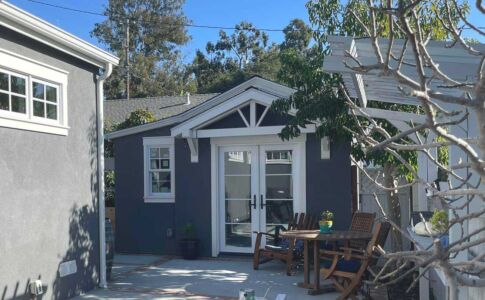 A view towards the ADU from the side yard of the house. The two structures share matching exterior finishes and detailing to promote a sense of continuity. Photo of garage conversion ADU in San Luis Obispo