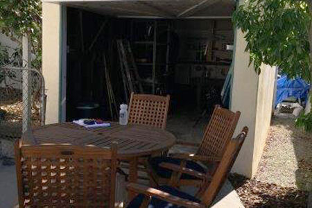 The exterior wall and roof structure of the garage, including the stucco and shingles, were kept for the ADU conversion. Insulation and structural retrofits were done on the interior, along with a new floor slab installed at a higher elevation to be above the flood plain. Photo of existing garage
