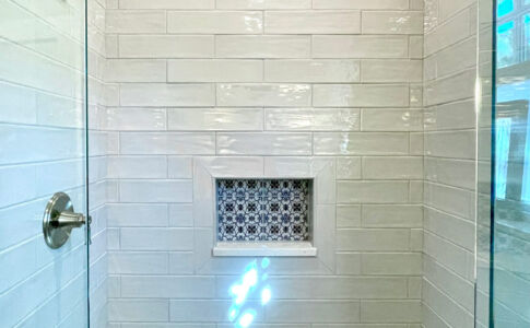 The completely remodeled guest bathroom boasts a generous custom shower stall, where once had been a bright cranberry-colored tub. Photo of remodeled shower with custom tile