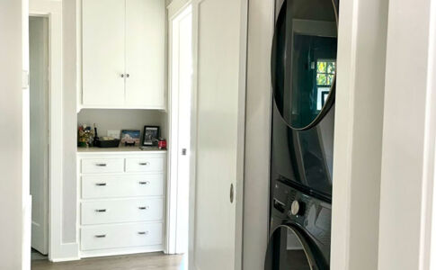 A new laundry closet was carved out of storage space in the hallway, conveniently located just outside the bedrooms. The existing laundry space had been off the kitchen, quite a distance away. Photo of barn door laundry closet - open