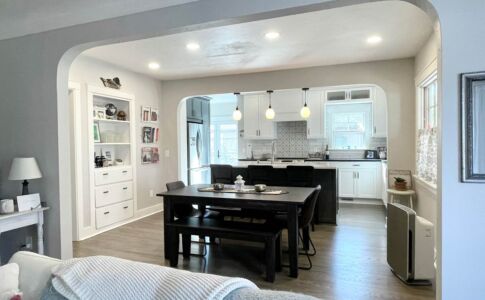 A light-filled, spacious, and modern open floor plan was created from what was a traditional boxed-in dining room and small galley kitchen. Enlarging the arched opening between living room and dining room, and creating a matching wide opening to the kitchen beyond, allows space to flow uninterrupted from room to room, while still giving each room it's own spatial definition. Photo of remodeled kitchen & dining room