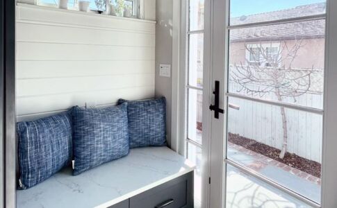 A banquette with storage and painted wood paneling bring character to the new entry vestibule. Photo of new entry vestibule addition