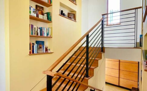 This stair hall is more than simply a circulation zone, it is a room unto itself. It features a window seat at the mid landing and built-in shelving on both sides to showcase favorite books and photos. Shelves, stairs, and handrail are all made of solid bamboo lumber. Photo of residential stairs with built-in shelves