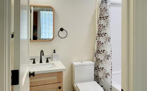 The bathroom shares the exposed concrete floors of the rest of the ADU, and features a high window to let in natural daylight while still safeguarding privacy. Bathroom with high window